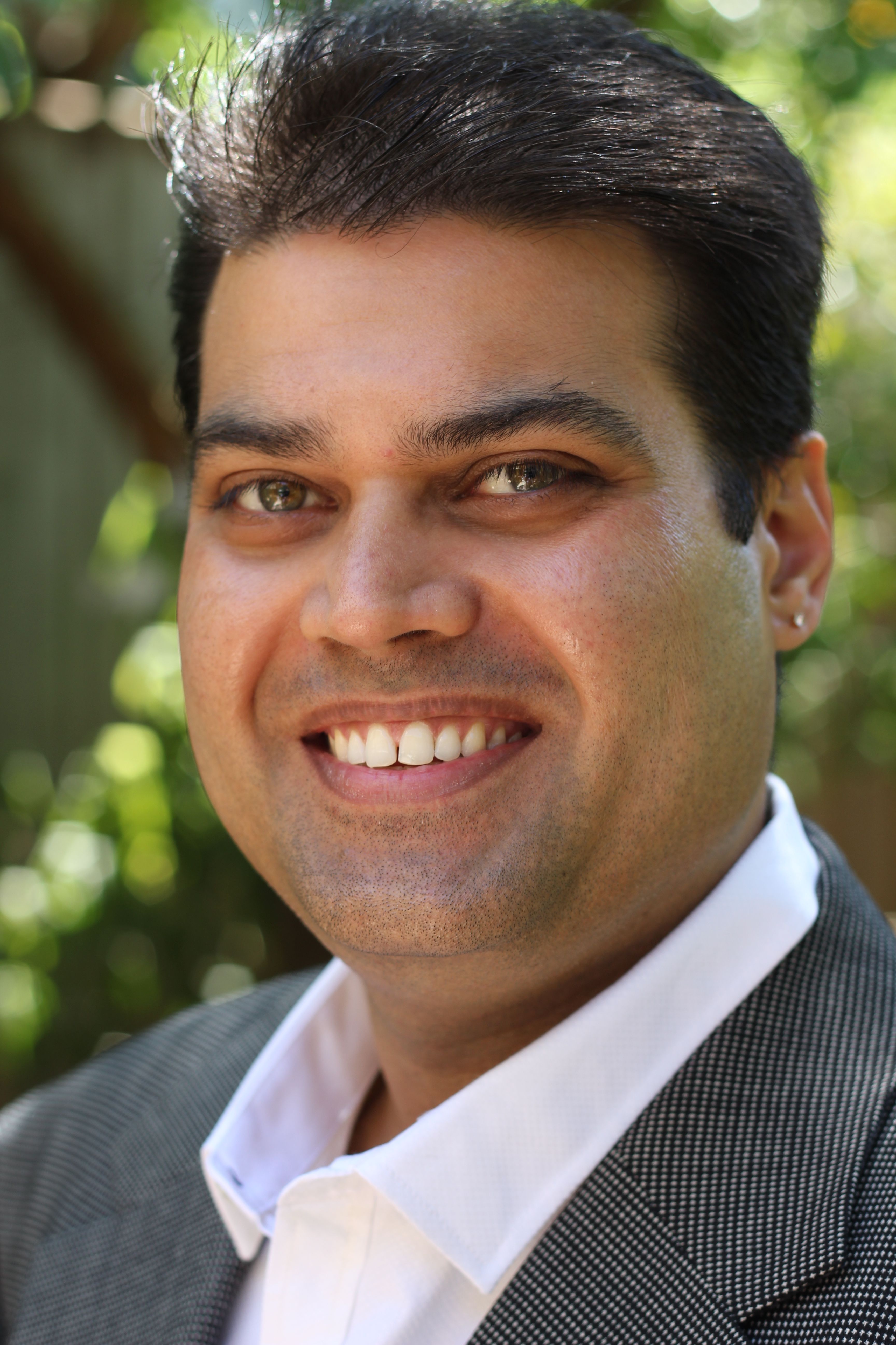 Ryan Gomez \u2014 relaxed professional portrait in grey blazer